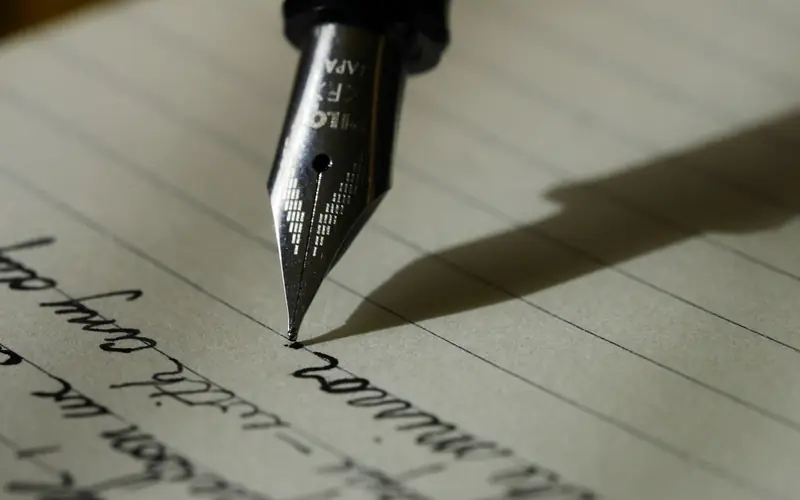 A fountain pen writing on a notebook page.