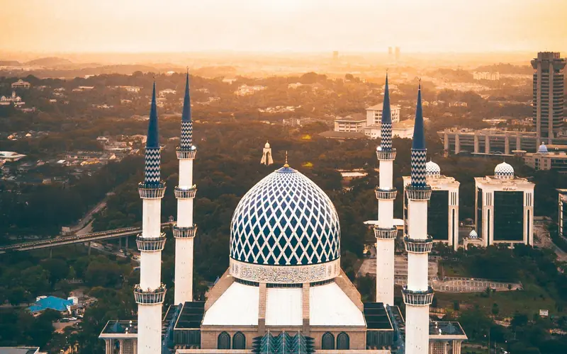 A mosque surrounded by trees at sunset.